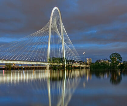 the margaret hunt hill bridge in the trinity river corridor the margaret hunt hill bridge in the trinity river corridor at dusk during a flood the bridge is lit and the sky is lit with colors